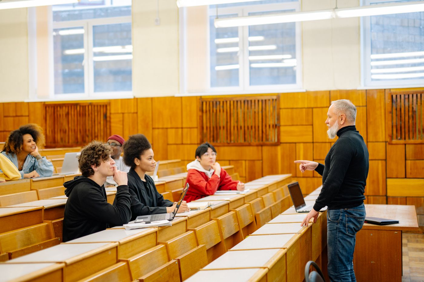 A lecturer speaking with students in a university lecture hall