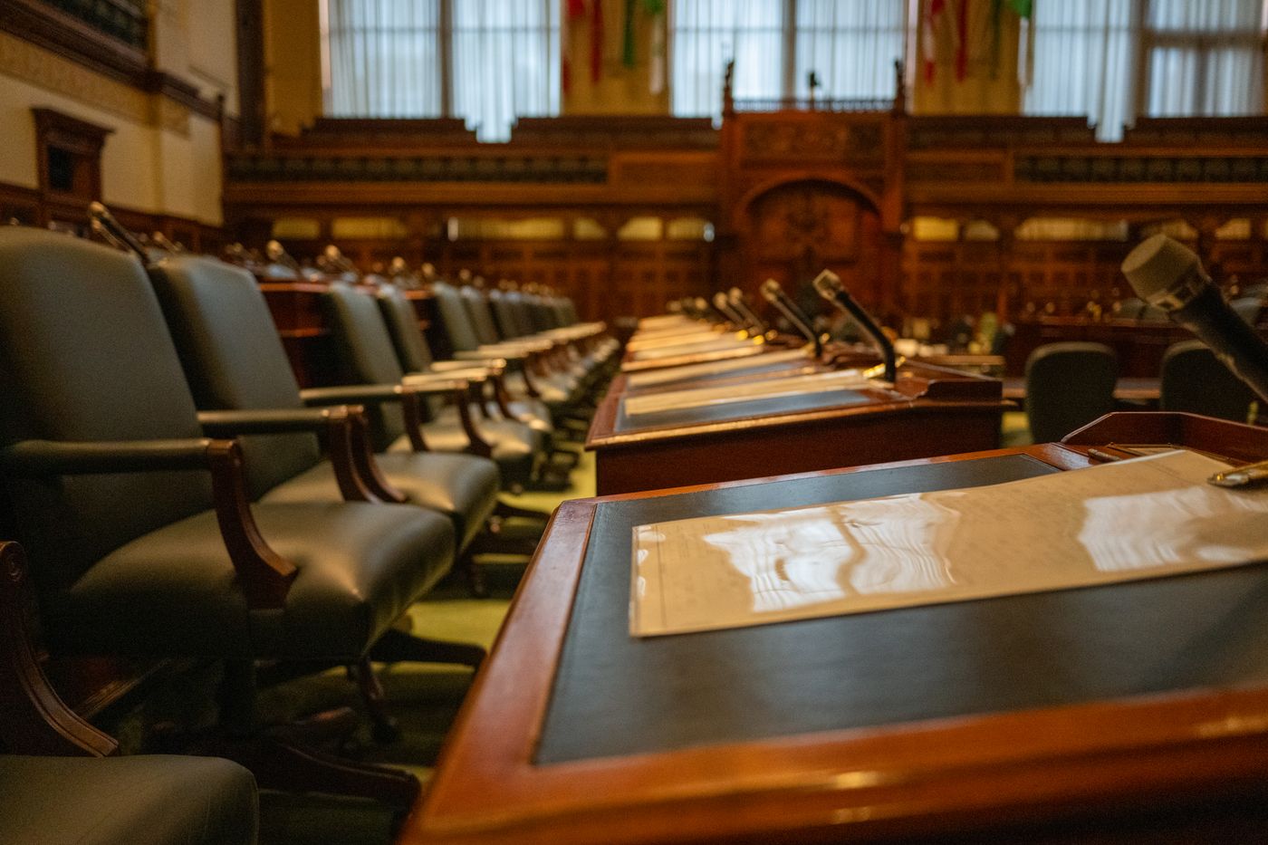 Rows of desks and microphones in an empty legislative chamber